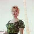 In this 1956 photograph taken on the set of Bus Stop by Milton H Greene, Marilyn Monroe is looking directly at the camera wearing red lipstick. Marilyn is wearing a green blouse in this on location image. 
