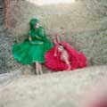 Leaning against a wall of hay, models Fiona Von Tyson and Nelly are wearing a green and red dress each with veils. This classic vintage fashion image was taken by Milton H. Greene in Spain for Life Magazine.